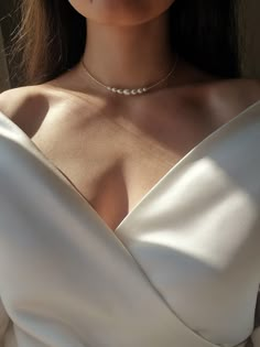 a woman in a white dress wearing a pearl necklace