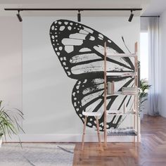 a black and white butterfly wall mural in an empty room with wooden flooring on the side