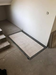 an empty room with some stairs and carpet on the floor in front of a white wall