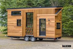 the tiny house is made from wood and has black trim on the door, windows, and sidewalls