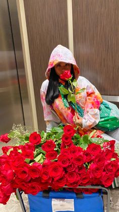 a woman sitting in front of a blue box filled with red roses