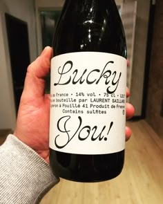 a person holding up a wine bottle with the words lucky you on it in french