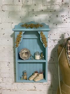 a blue shelf sitting next to a mannequin wearing a dress and necklaces