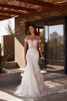 a woman in a white wedding dress standing on a patio with her hand on her hip