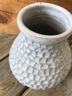 a white vase sitting on top of a wooden table