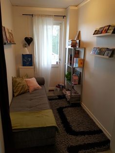 a small room with a bed, bookshelf and window