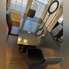 a glass table with two chairs next to it in front of a window covered by blinds