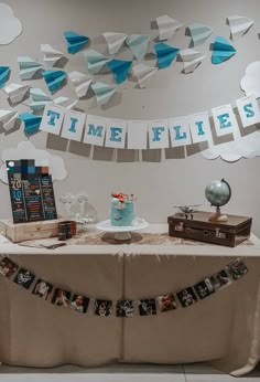 a table topped with a cake covered in blue frosting next to a sign that says time flies