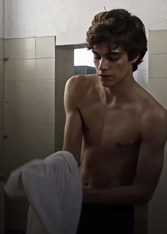 a shirtless man standing in a bathroom next to a sink and towel hanging on the wall