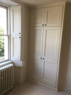 an empty room with white cupboards and a radiator in front of the window