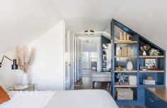 a bed sitting under a window next to a book shelf filled with books and vases