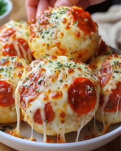 four mini pizzas with cheese and sauce in a white bowl