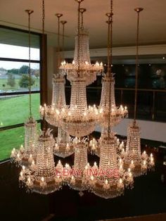 a chandelier hanging from the ceiling in a room with large windows and grass outside