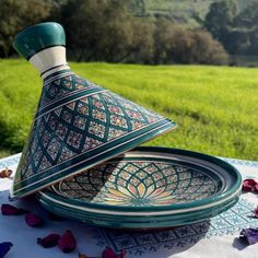 two plates with designs on them sitting on a table in the middle of a field