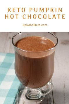 a glass filled with hot chocolate sitting on top of a blue and white checkered table cloth