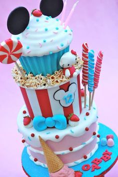 a mickey mouse birthday cake with cupcakes, candy and lollipops