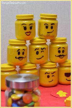 there are many yellow jars that have faces painted on them and some candy in front of them