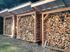 several stacks of logs are stacked next to each other in front of a wooden structure