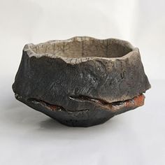 an old wooden bowl sitting on top of a white table next to a black object