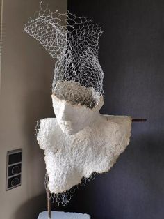 a sculpture made out of rock and wire on top of a white block of paper