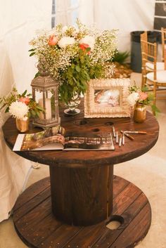 a table with flowers and pictures on it in front of a white tented area