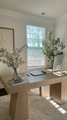 two vases with flowers are sitting on a table in front of a large window