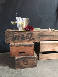 two wooden crates sitting next to each other with wine glasses and flowers on top of them