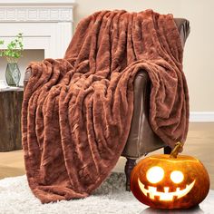 a chair with a pumpkin sitting on top of it next to a blanket that is shaped like a jack - o'- lantern