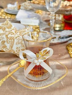 a glass cup with a bow on it sitting on a plate next to other place settings