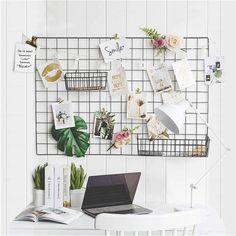 a laptop computer sitting on top of a white desk next to a plant and other items