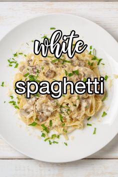 a white plate topped with pasta covered in mushrooms and parsley next to a fork