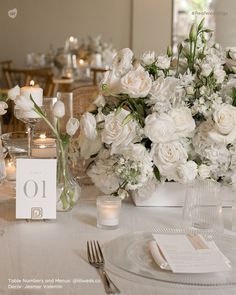 the table is set with white flowers and place cards for guests to sit down at