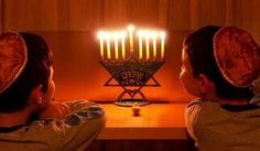 two children looking at a hanukkah menorah with candles in it