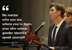 a man standing at a podium in front of a microphone with a quote on it