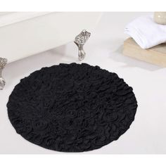 a black round rug sitting on top of a white floor next to a bath tub