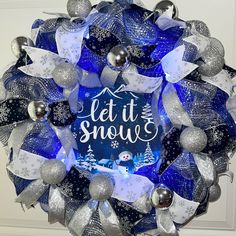 a blue and silver christmas wreath with let it snow written on the front in white lettering