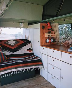 a kitchen area with cabinets and a bed in the back ground next to a window