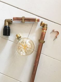 an old fashioned light bulb and pipe on the floor next to other plumbing tools,