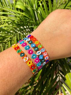 a person's arm with three bracelets on top of it and palm trees in the background