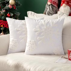 two white pillows sitting on top of a couch next to a christmas tree and other decorations