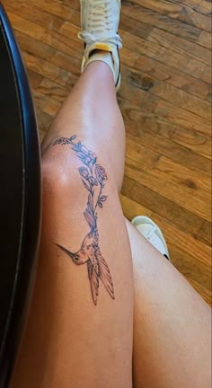 a woman's leg with a tattoo on it that has a bird and flowers on it