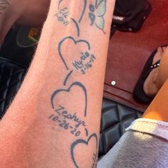 two people sitting next to each other with tattoos on their arms and legs, one has a small heart in the middle