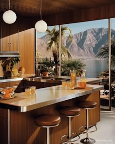 a kitchen with an island and bar stools in front of a large window overlooking the mountains