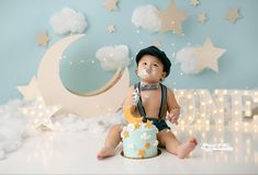 a baby sitting on the floor with a cake in front of him and stars around it