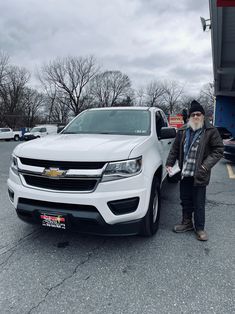 a man standing next to a white truck in a parking lot