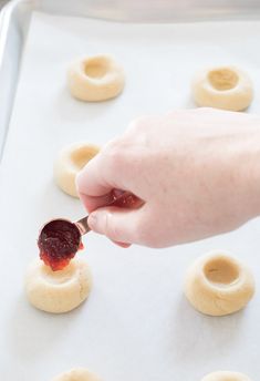 someone is spreading jam on doughnut holes