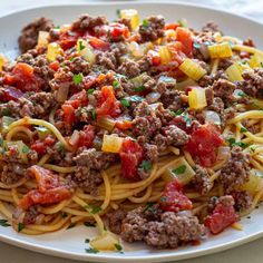 a plate of spaghetti with meat and vegetables on the side, ready to be eaten