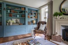 a living room with blue bookcases and a chair in front of a fireplace