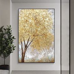 a large painting hanging on the wall next to a potted plant in a living room