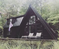 a small cabin in the woods with lawn chairs